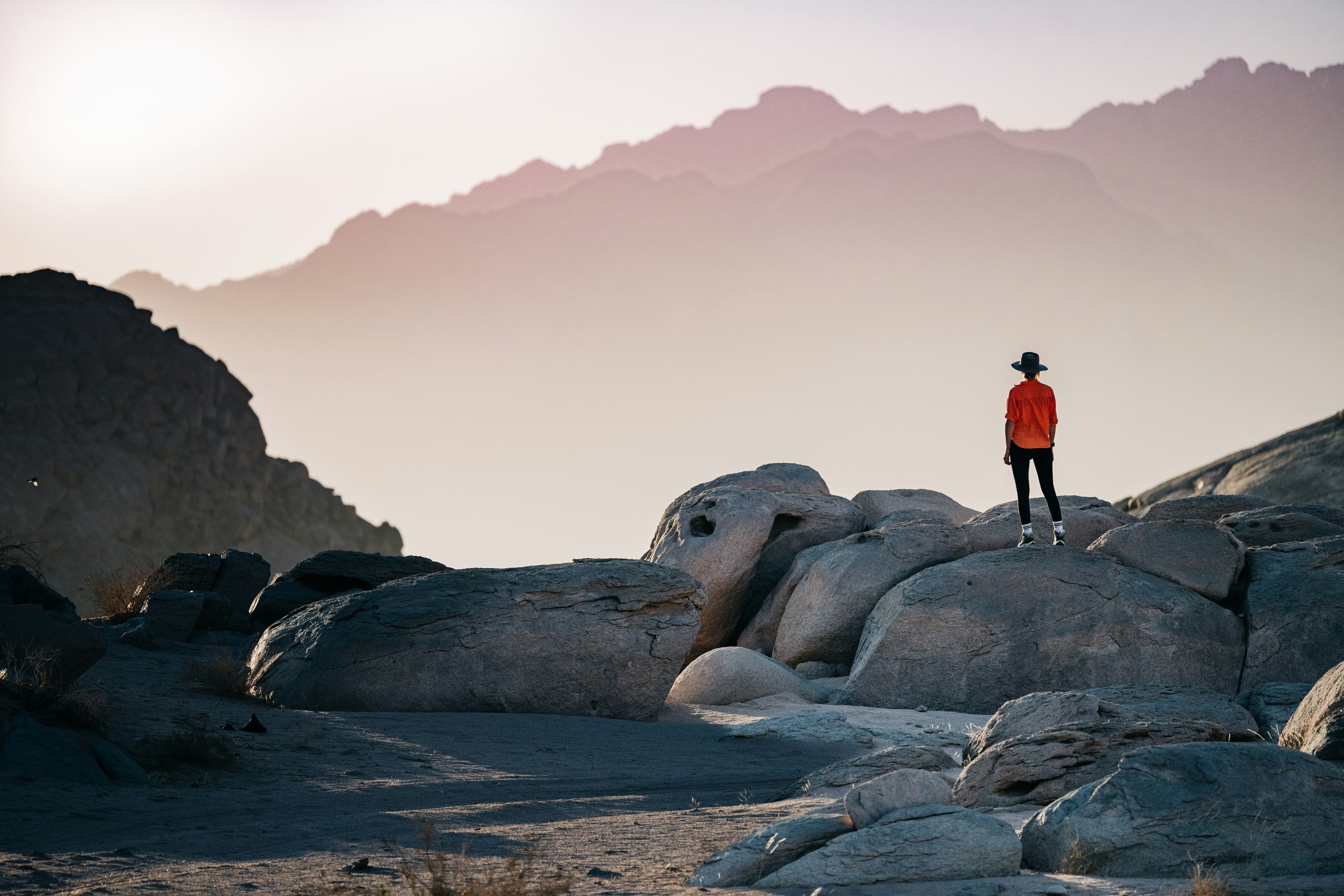 Traveler standing on desert rocks at dusk